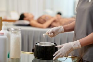 Waxing treatment at a spa in Auburn, AL. Technician prepares wax while client relaxes on table.