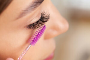 Close-up of eyelash styling with a mascara wand in Auburn, AL. Perfect eyelashes beauty treatment. Great lash lift Auburn.