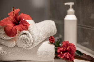 Rolled white towels and hibiscus flowers in a spa setting, Auburn, AL, enhancing relaxation and luxury.
