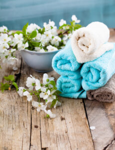 Rolled towels and blossoms arranged on rustic wood, Auburn, AL spa ambiance.