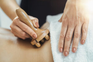 Massage therapy using wood massager tool in Auburn, AL spa. Relaxation and wellness session depicted.